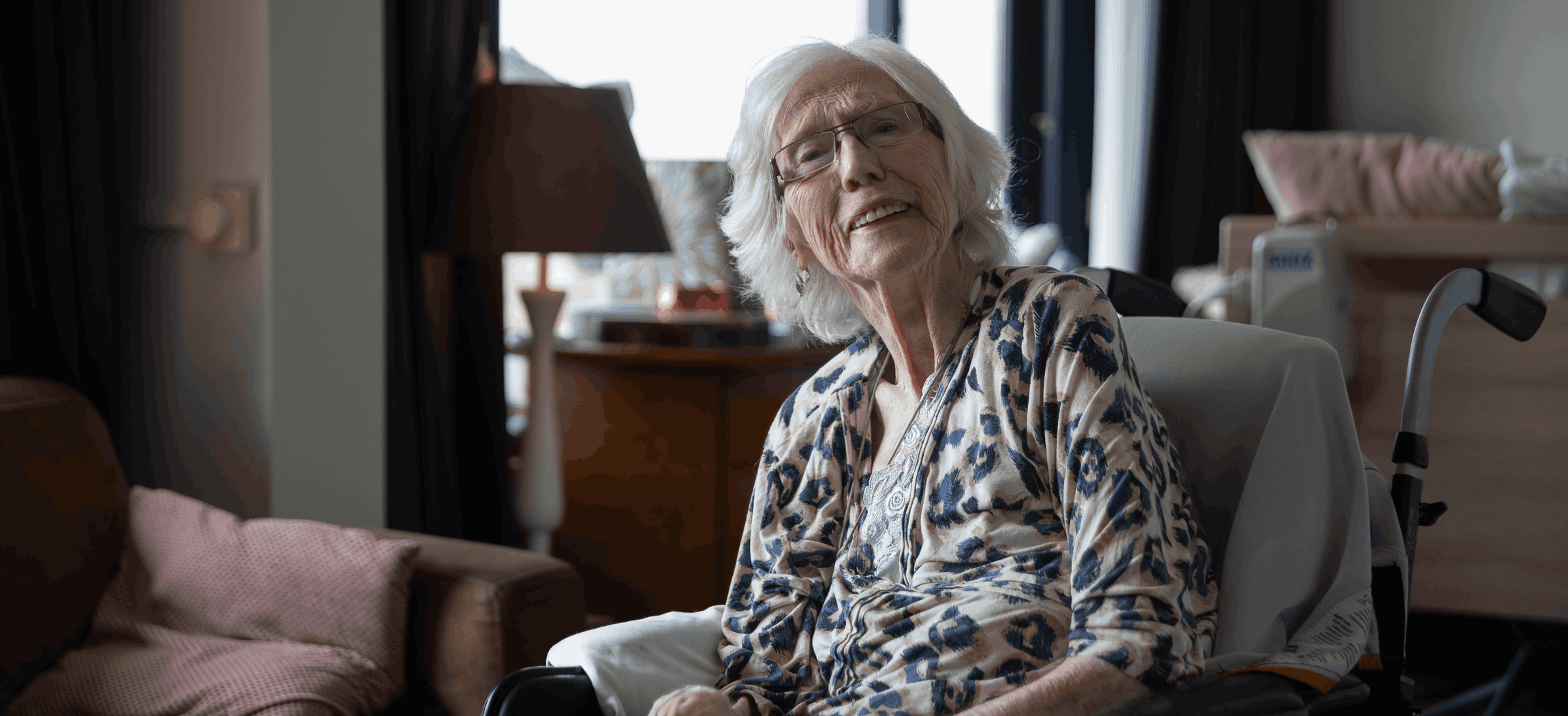 Verzorgende met krullend haar geeft oude vrouw drinken met rietje