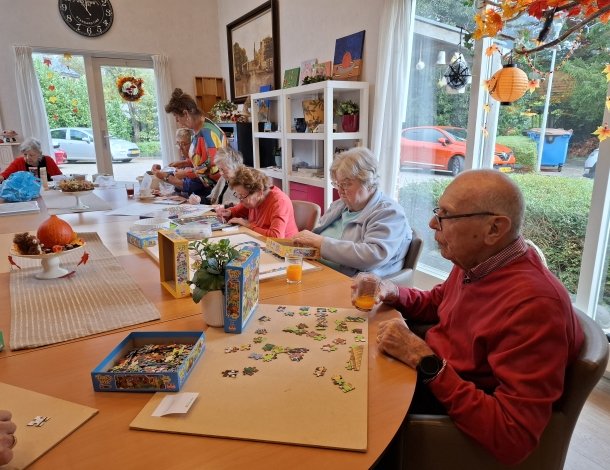 Blije oude vrouw met wit haar verzorgt samen de geraniums buiten op terras
